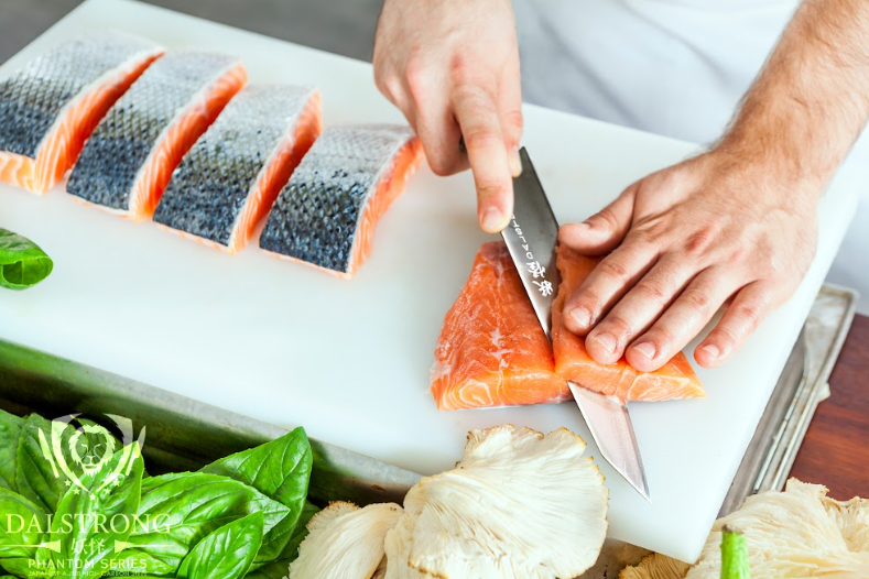 A photo of a hand slicing a samon meat using Kiritsuke Chef's Knife 9.5" Phantom Series | herniaquestions