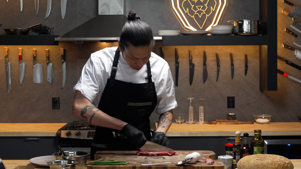 A man with black apron slicing meat on the Teak Cutting Board Lionswood