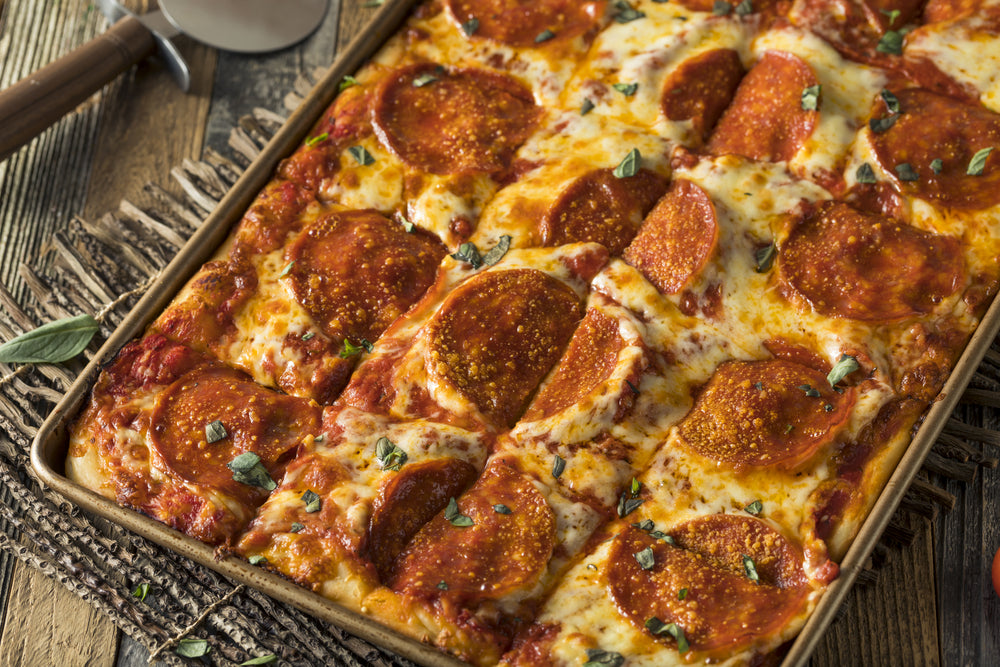 Homemade Sicilian Style Pizza with pepperoni still in the baking tray on a kitchen table